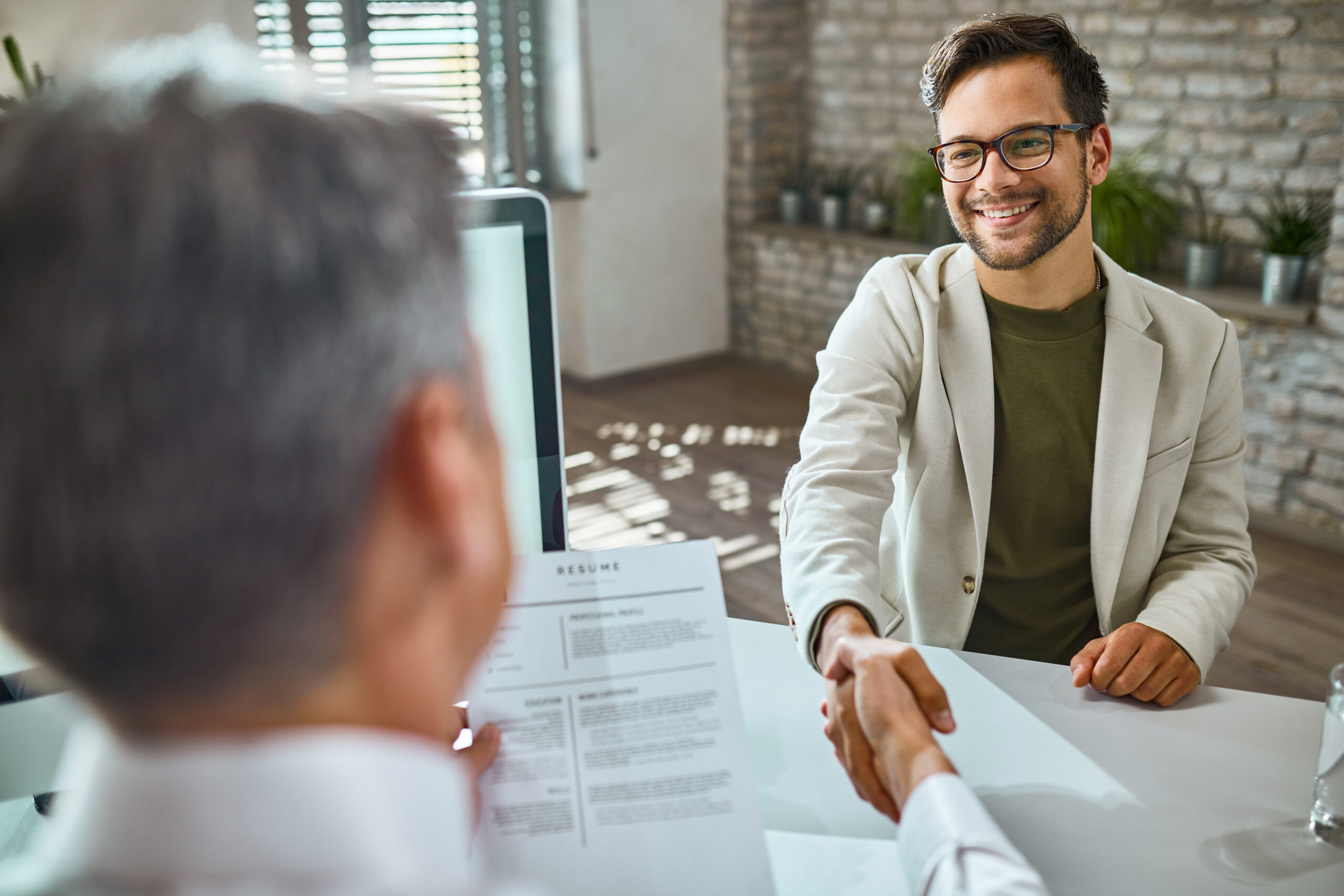 Happy male candidate greeting a member of human resource team on a job interview in the office.