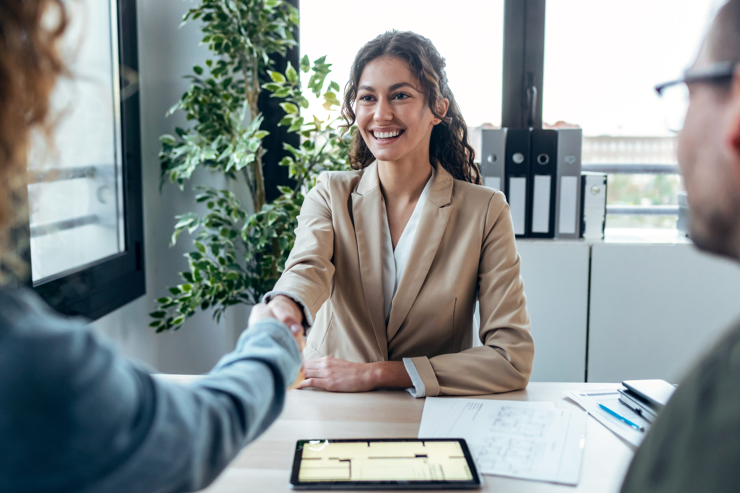 Shot of attractive real-estate agent shaking hands with young couple after signing agreement contract in a real estate