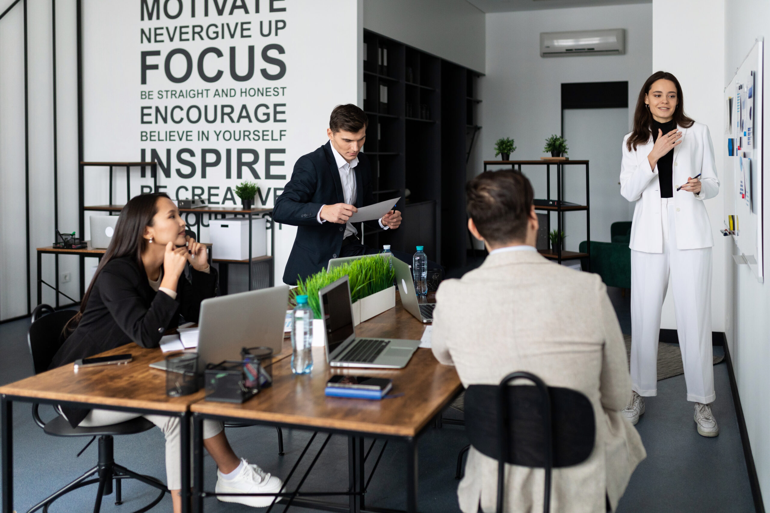 woman giving a report on time brainstorm in a stylish office in front of different national staff.